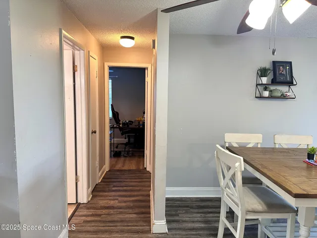 a view of a hallway to a livingroom with wooden floor and furniture