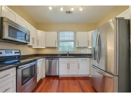 a kitchen with stainless steel appliances granite countertop a refrigerator a stove a sink and a microwave