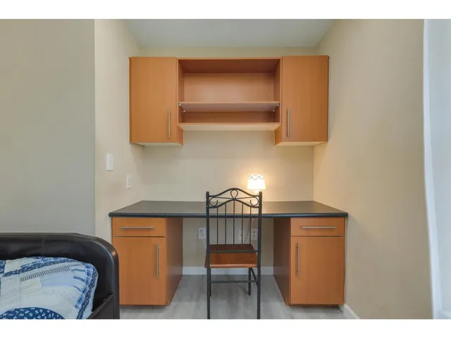 a bedroom with a bed and a lamp on dresser