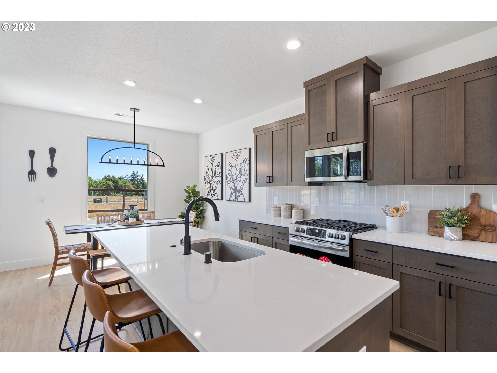 715 Northwest 175th Way Ridgefield, WA 98642 - Photo 4 of 26 a kitchen with stainless steel appliances kitchen island granite countertop a sink a stove a microwave a dining table and chairs