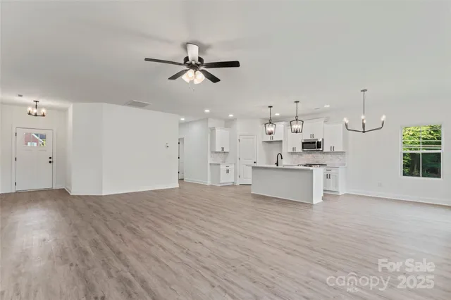 a view of a kitchen with kitchen island a sink wooden floor and a refrigerator