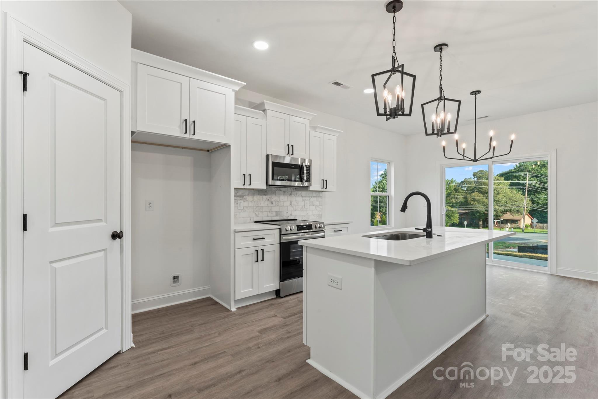 1 Morehead Road Harrisburg, NC 28075 - Photo 9 of 32 a kitchen with stainless steel appliances granite countertop a sink a stove a refrigerator and island with wooden floor
