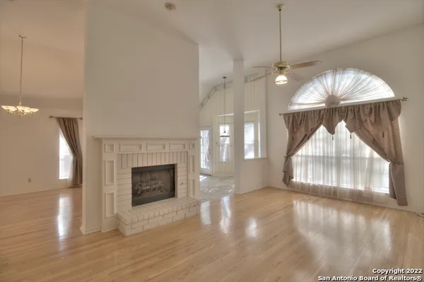 an empty room with wooden floor fireplace and windows