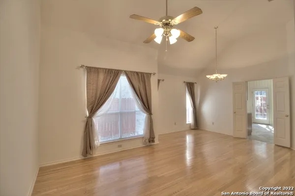 an empty room with wooden floor fan and windows