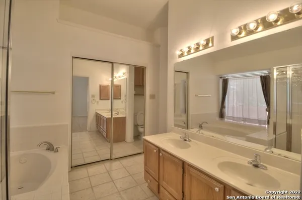 a bathroom with a double vanity sink mirror and bathtub