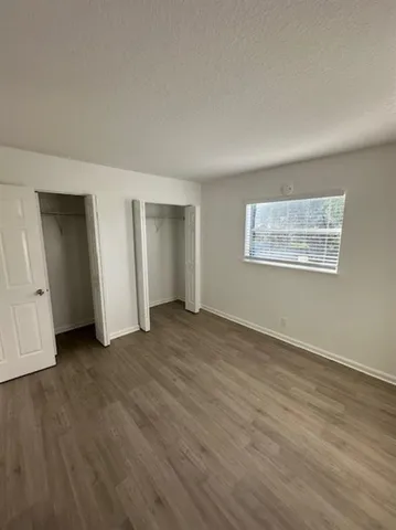 a view of an empty room with wooden floor and closet