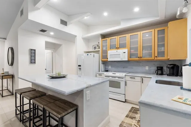 a kitchen with a stove a sink dishwasher a kitchen island with wooden cabinets and floor