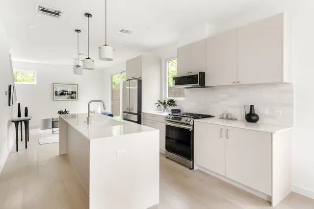 a kitchen with a sink a stove and white cabinets