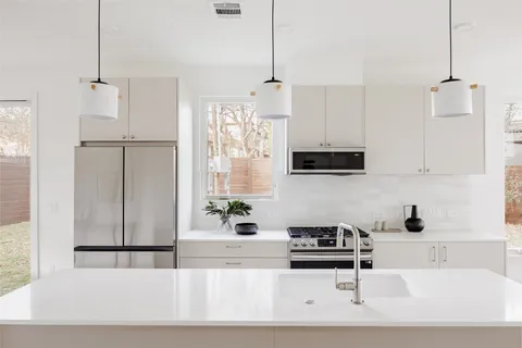 a kitchen with stainless steel appliances granite countertop a sink a stove and a refrigerator