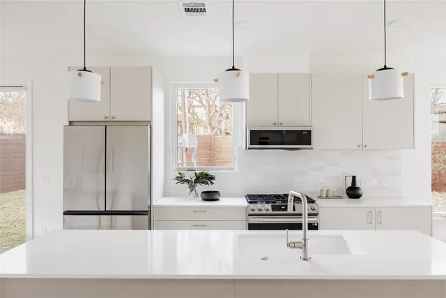 a kitchen with stainless steel appliances granite countertop a sink a stove and a refrigerator