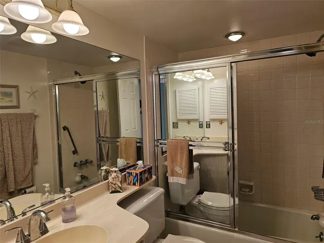 a bathroom with a double vanity sink toilet mirror and shower