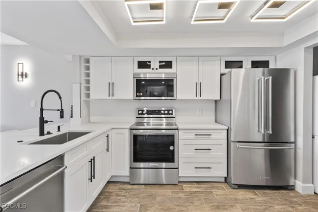 a kitchen with stainless steel appliances a refrigerator stove and white cabinets