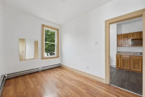 a view of an empty room with a window and wooden floor