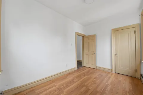 a view of an empty room with wooden floor and closet