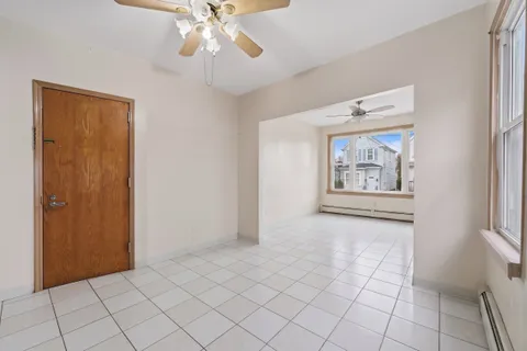 a view of an empty room with window and chandelier fan