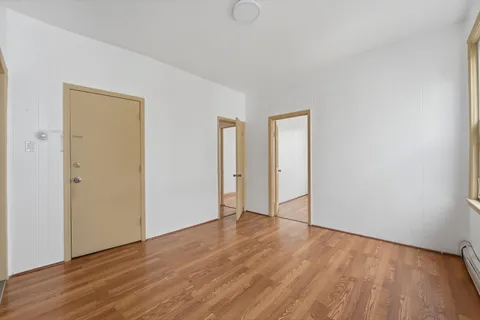 a view of an empty room with wooden floor and closet