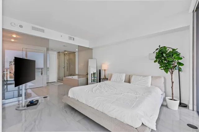 a bedroom with a bed and a flat tv screen on dresser