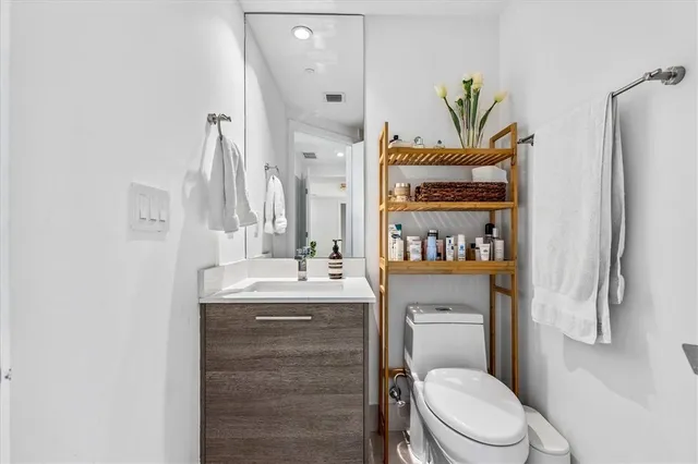 a bathroom with a granite countertop toilet sink and mirror
