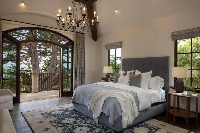 a bedroom with a large bed a chandelier and dresser