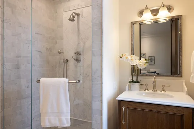 a bathroom with a sink a mirror a vanity and a shower