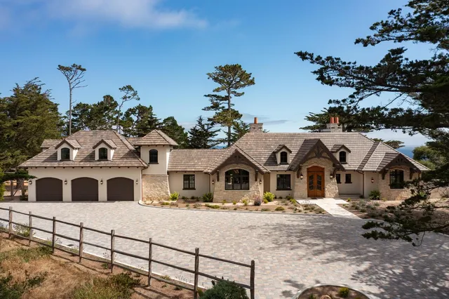 a front view of a house with large trees