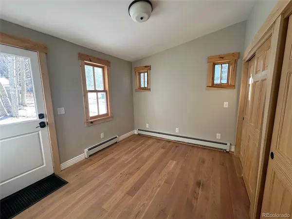 a view of an empty room with wooden floor and a window