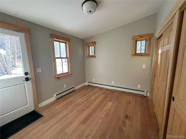 a view of an empty room with wooden floor and a window