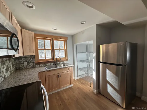 a kitchen with granite countertop a refrigerator a sink a stove and island