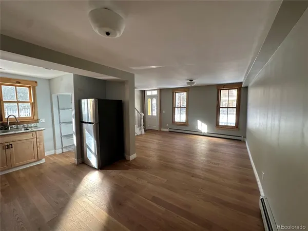 a view of an empty room with window and wooden floor