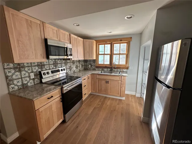 a kitchen with a sink a counter top space stainless steel appliances a window and a counter top space