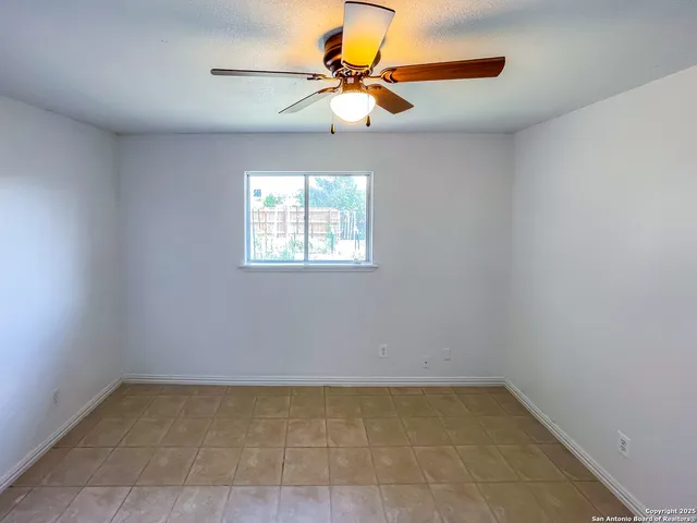 an empty room with chandelier fan