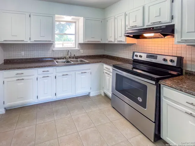 a kitchen with granite countertop white cabinets stainless steel appliances and sink