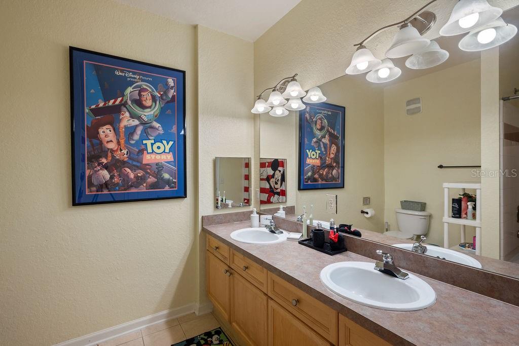 302 Terrace Ridge Circle, Unit 302 Davenport, FL 33896 - Photo 13 of 23 a bathroom with a sink a mirror and a painting on the wall