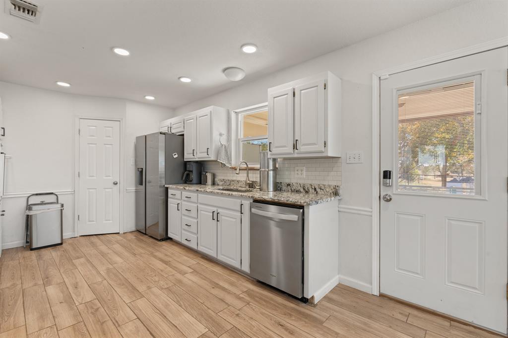 1013 Highland Road Cleburne, TX 76033 - Photo 14 of 33 a large kitchen with stainless steel appliances granite countertop a stove a sink dishwasher and a refrigerator with wooden floor