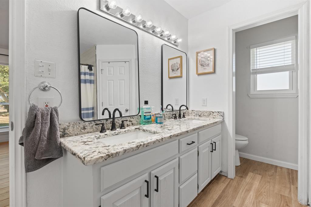 1013 Highland Road Cleburne, TX 76033 - Photo 26 of 33 a bathroom with a granite countertop sink and a mirror