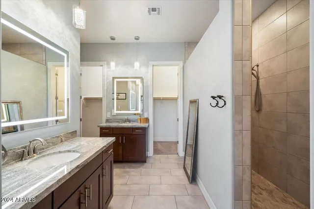 a spacious bathroom with a granite countertop sink a mirror and a shower