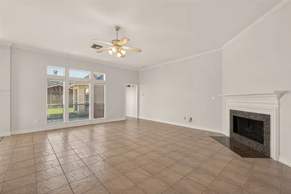a view of an empty room with chandelier fan and fire place