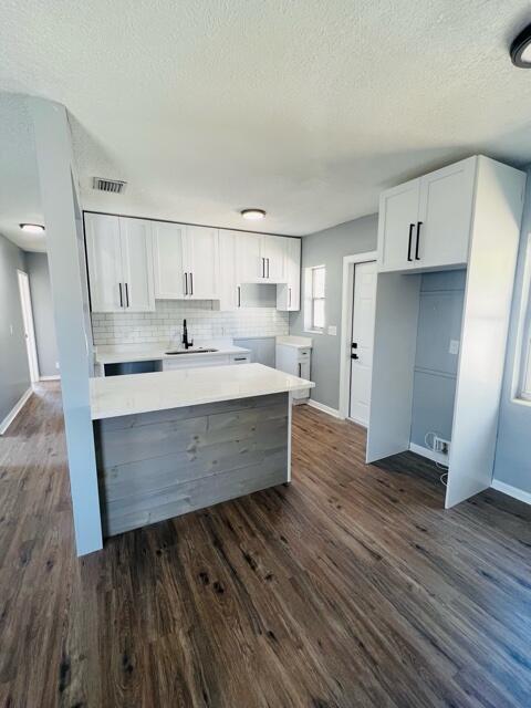 a room with wooden floors and white cabinets