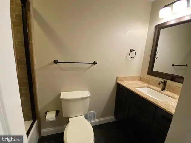 a bathroom with a granite countertop toilet sink and mirror