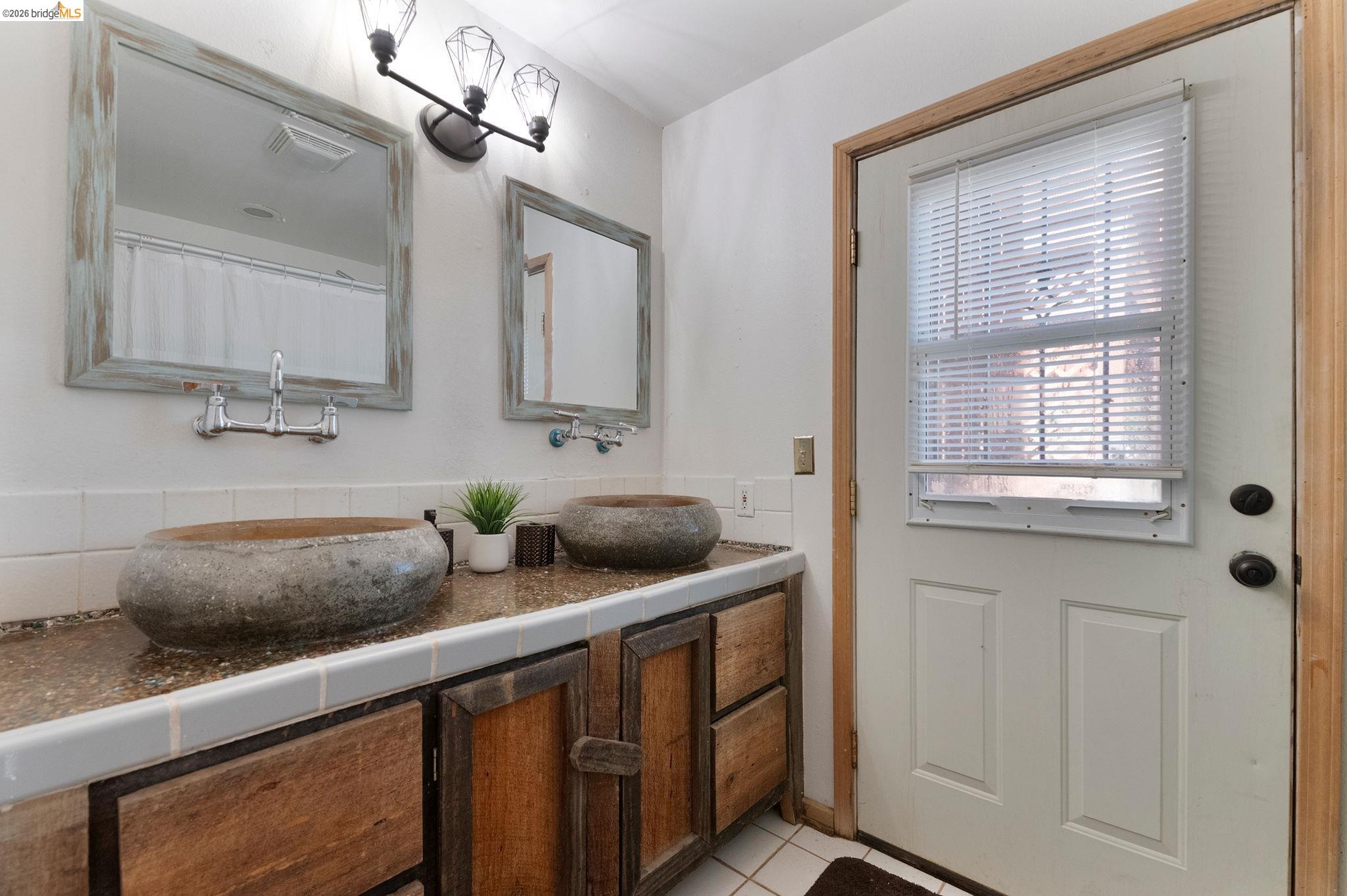 22963 Robertson Ranch Road Sonora, CA 95370 - Photo 54 of 90 Double vanity with vessel sinks, wood-finish cabinetry, and a textured countertop