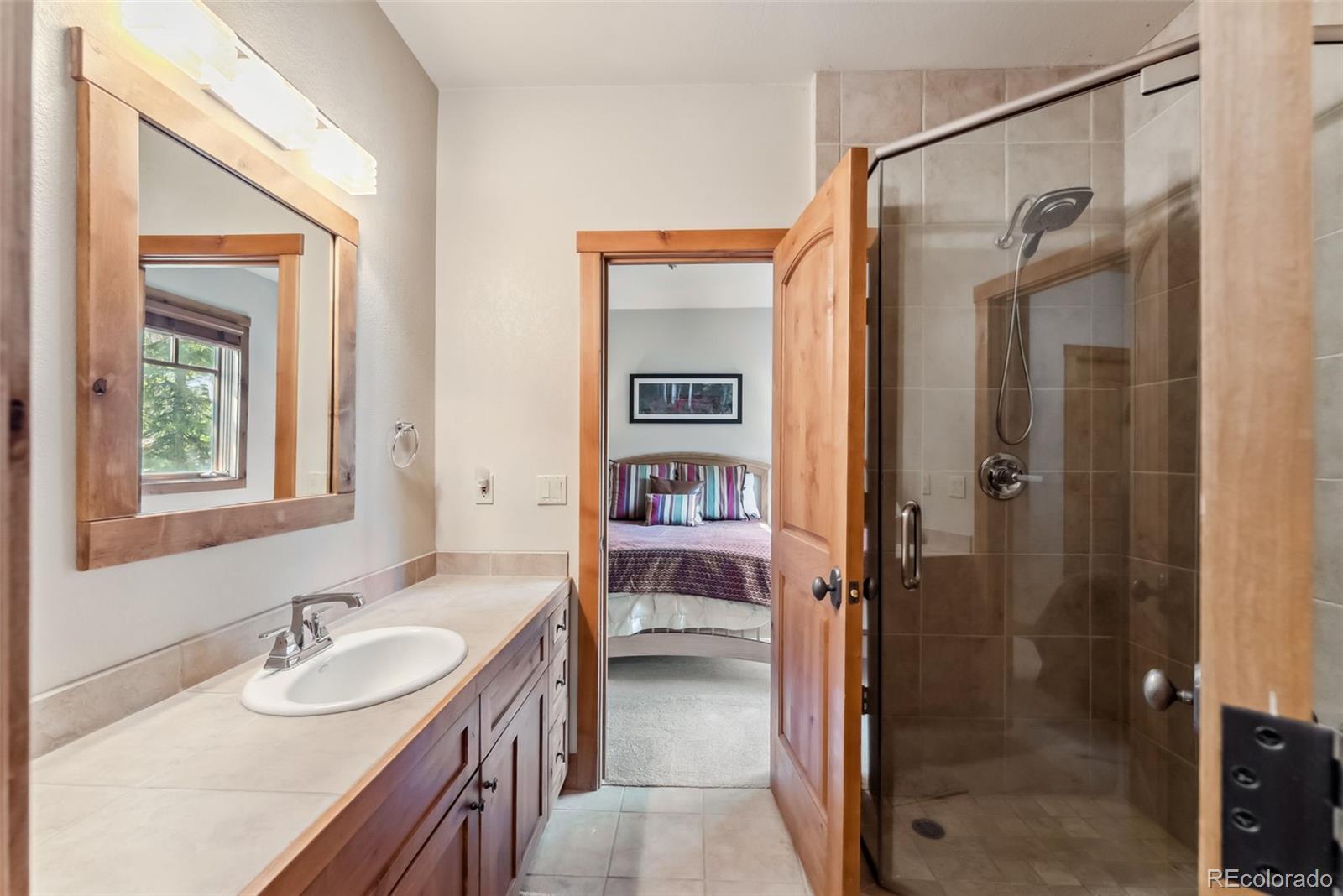 0024 Rasor Drive Dillon, CO 80435 - Photo 34 of 37 a en suite bathroom with a granite countertop sink a mirror a shower and a bathtub