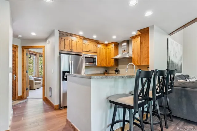 a kitchen with stainless steel appliances granite countertop a dining table chairs refrigerator and sink
