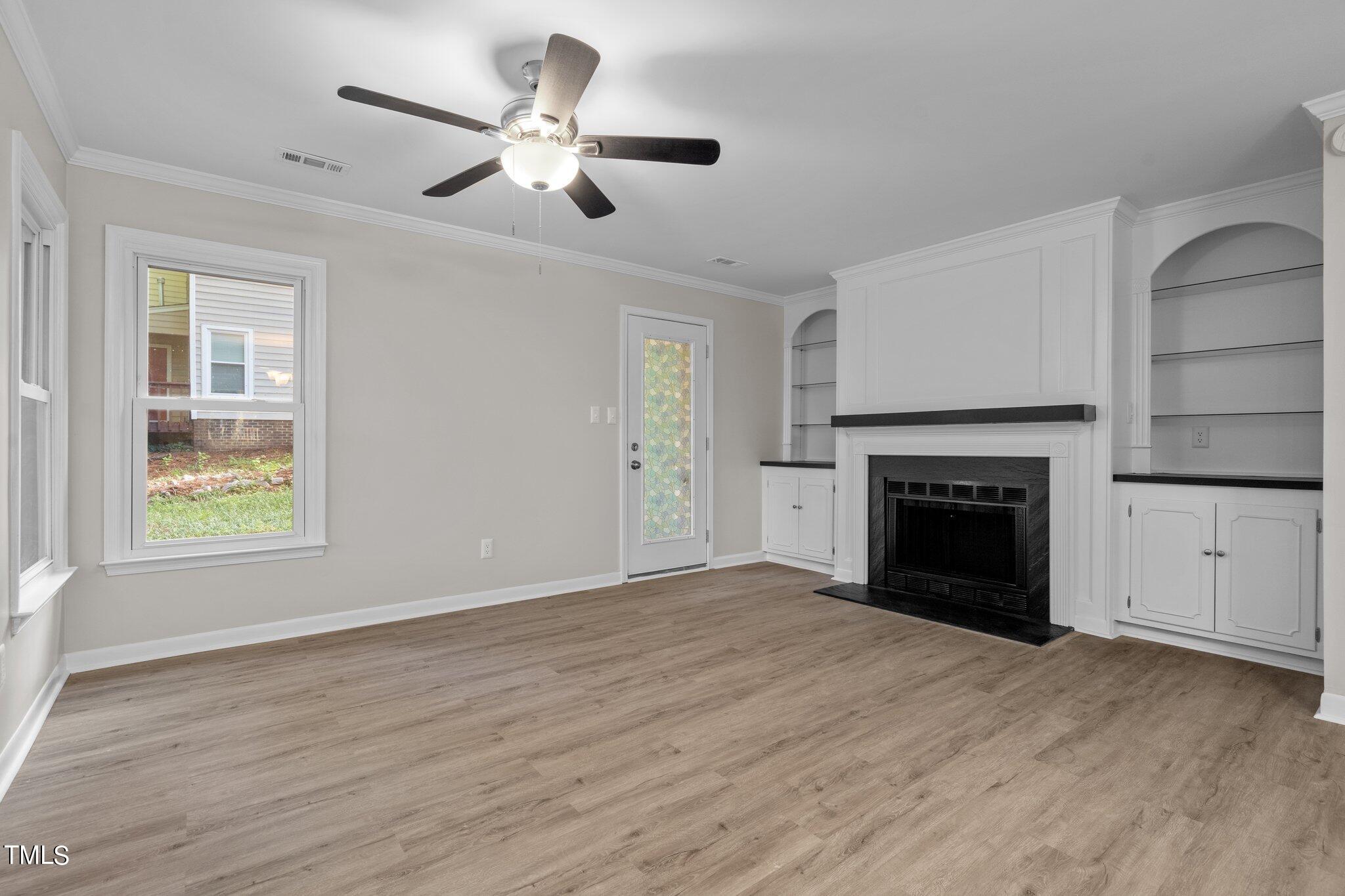 3408 Comstock Road Raleigh, NC 27604 - Photo 11 of 33 an empty room with windows fireplace and a ceiling fan