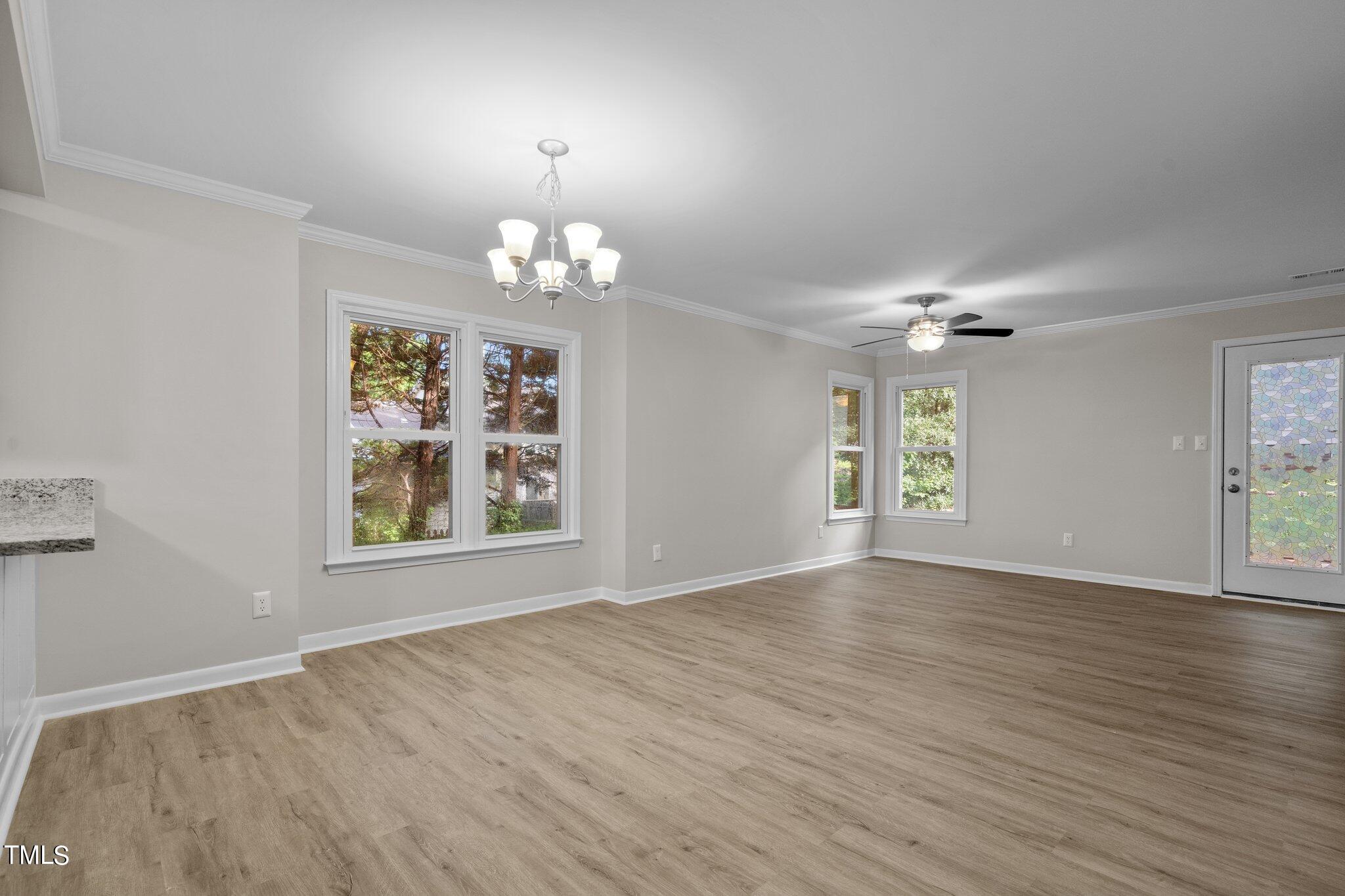 3408 Comstock Road Raleigh, NC 27604 - Photo 6 of 33 an empty room with wooden floor chandelier and windows