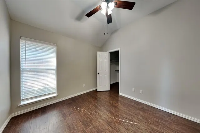 an empty room with wooden floor fan and windows