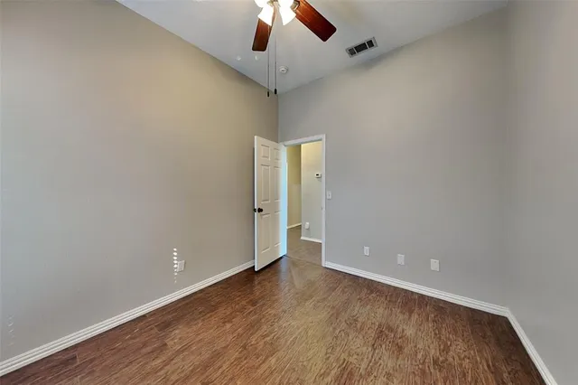 an empty room with a ceiling fan and wooden floor