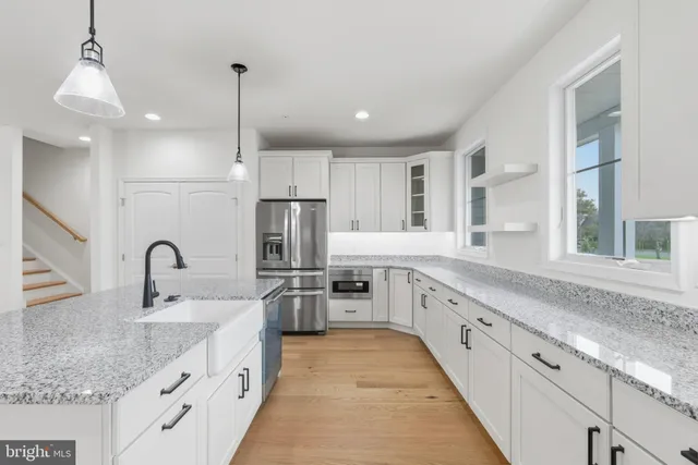 a large kitchen with granite countertop a large counter top a sink stainless steel appliances and cabinets