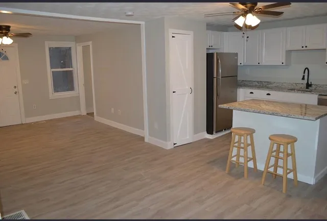 a kitchen with stainless steel appliances granite countertop a refrigerator a sink dishwasher and a stove with wooden floor