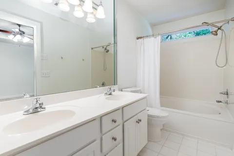 a bathroom with a sink double vanity granite tub shower and a mirror