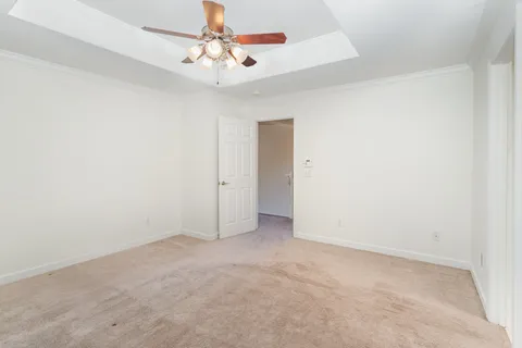 an empty room with a chandelier fan and windows